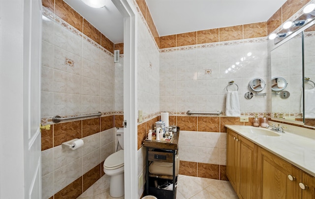 bathroom featuring toilet, tile patterned flooring, vanity, and tile walls