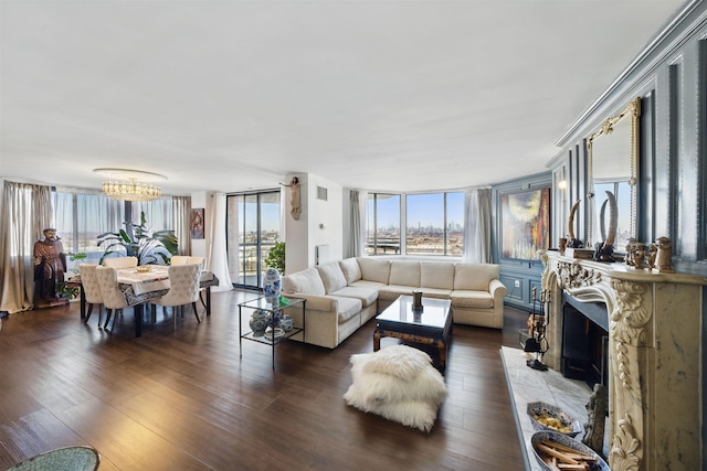 living area featuring a fireplace with raised hearth, dark wood-style flooring, and a chandelier