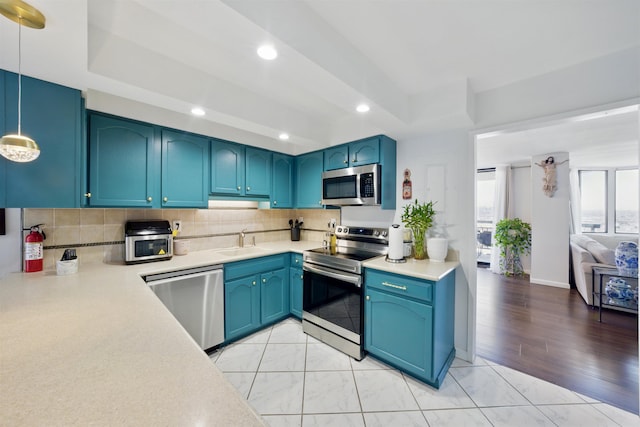 kitchen with decorative backsplash, appliances with stainless steel finishes, light countertops, a sink, and recessed lighting