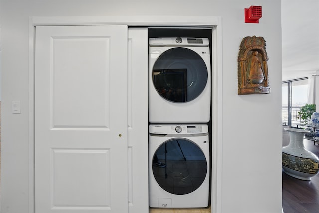 washroom featuring laundry area, stacked washer / drying machine, and wood finished floors