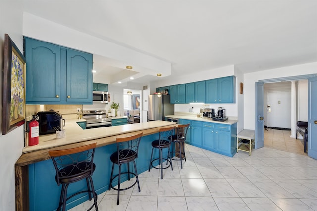 kitchen featuring appliances with stainless steel finishes, light countertops, a peninsula, and blue cabinetry