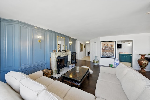 living area with a fireplace with raised hearth and wood finished floors