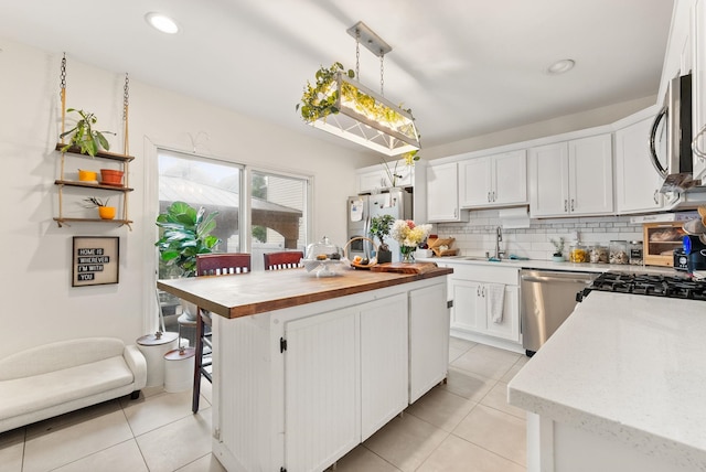 26 E 49th St, Bayonne, NJ 07002 - kitchen featuring a sink, appliances with stainless steel finishes, light tile patterned flooring, butcher block countertops, and white cabinetry