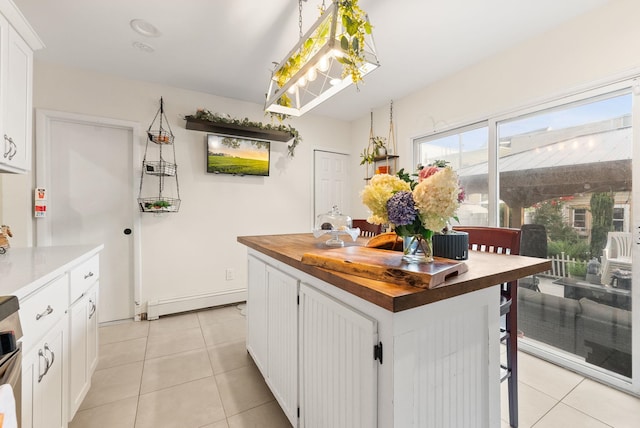 26 E 49th St, Bayonne, NJ 07002 - kitchen with butcher block counters, a baseboard heating unit, light tile patterned floors, white cabinets, and range