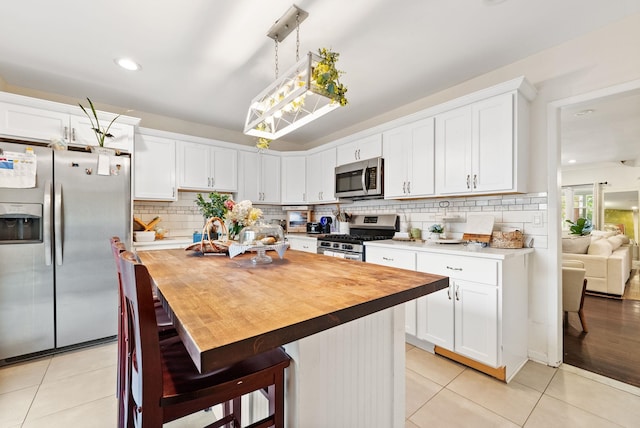26 E 49th St, Bayonne, NJ 07002 - kitchen with stainless steel appliances, butcher block counters, light tile patterned floors, and recessed lighting