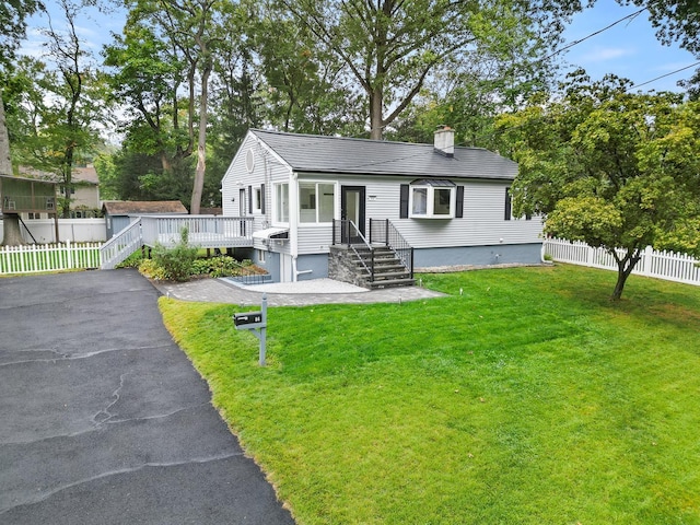 view of front of home with a front yard and a wooden deck