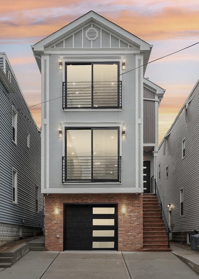 27 E 16th St Unit 2, Bayonne, NJ 07002 - modern home featuring a garage, brick siding, concrete driveway, a balcony, and stucco siding