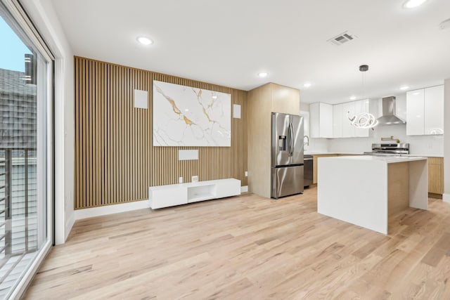 27 E 16th St Unit 2, Bayonne, NJ 07002 - kitchen featuring stainless steel appliances, wall chimney range hood, light countertops, light wood-style flooring, and hanging light fixtures