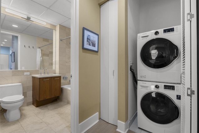 clothes washing area featuring laundry area, a sink, and stacked washing maching and dryer