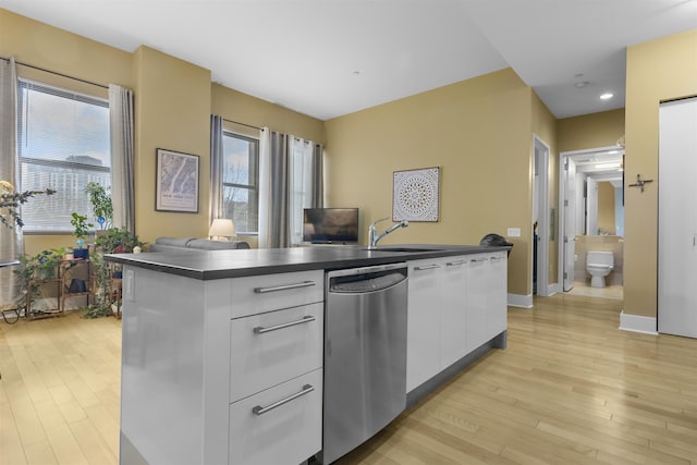 kitchen with dark countertops, modern cabinets, stainless steel dishwasher, white cabinetry, and a wealth of natural light