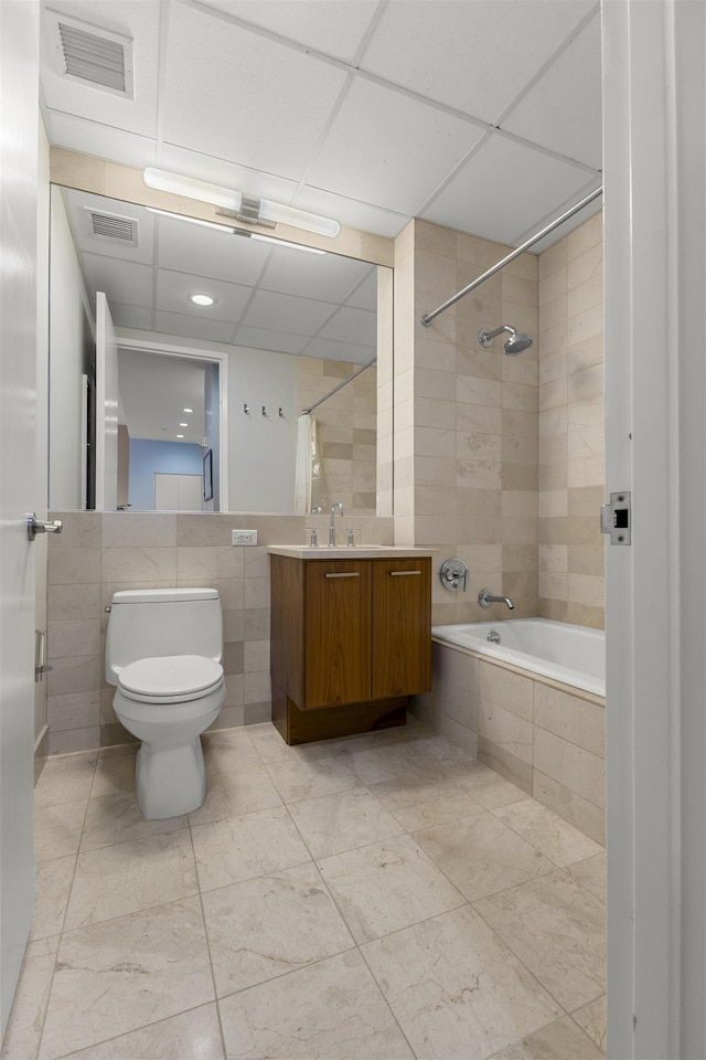 bathroom with toilet, visible vents, tile walls, and tiled shower / bath combo