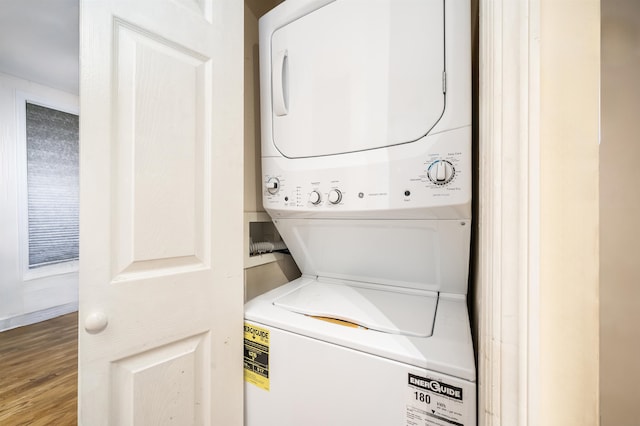 clothes washing area featuring stacked washing maching and dryer and wood-type flooring