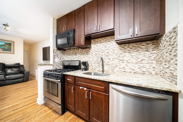 kitchen featuring light stone counters, decorative backsplash, sink, light wood-type flooring, and appliances with stainless steel finishes