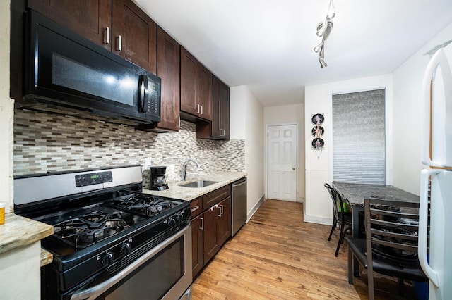 kitchen featuring appliances with stainless steel finishes, dark brown cabinetry, decorative backsplash, sink, and light hardwood / wood-style flooring