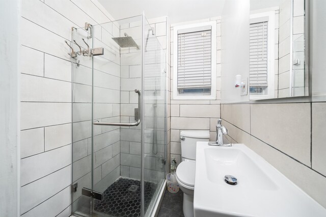 bathroom featuring toilet, tile walls, and a shower with shower door