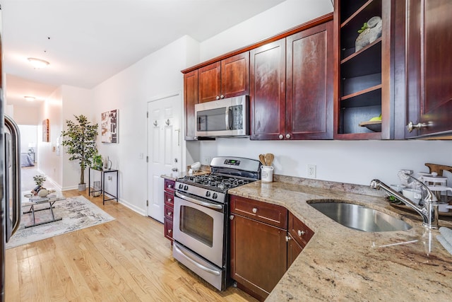 kitchen featuring light stone countertops, sink, light wood-type flooring, and appliances with stainless steel finishes