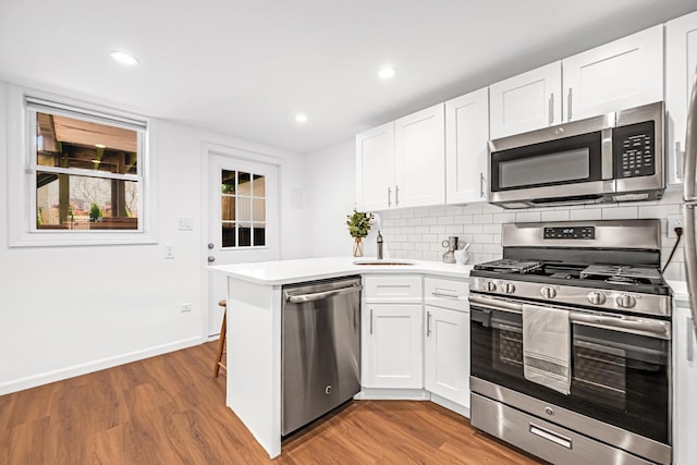 127 Jane St, Weehawken, NJ 07086 - kitchen with stainless steel appliances, light wood finished floors, a peninsula, baseboards, and recessed lighting