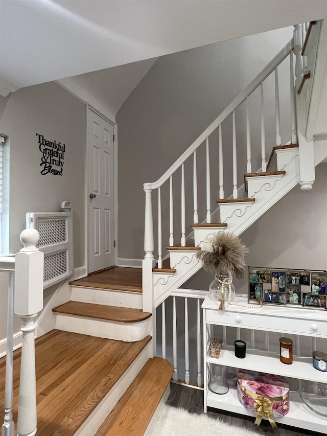 stairway with hardwood / wood-style flooring and vaulted ceiling