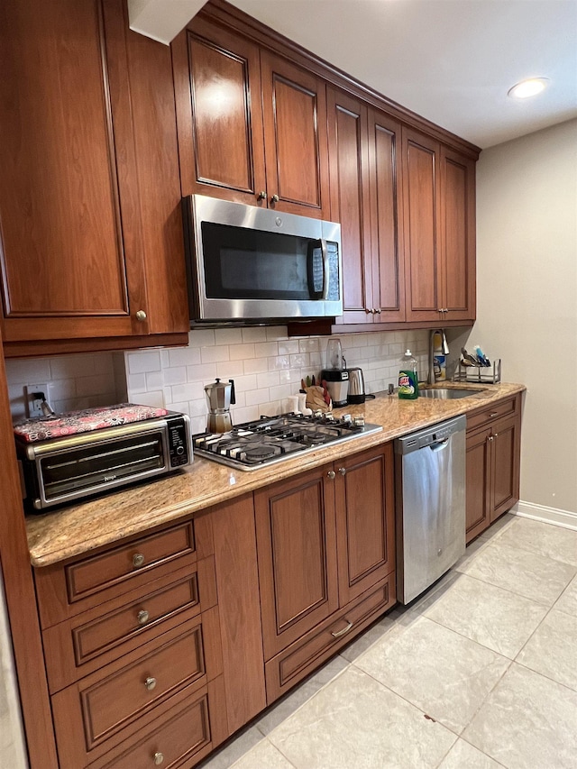 kitchen with backsplash, appliances with stainless steel finishes, light tile patterned floors, and sink