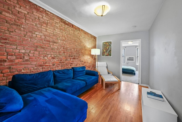 living room featuring hardwood / wood-style floors, crown molding, and brick wall