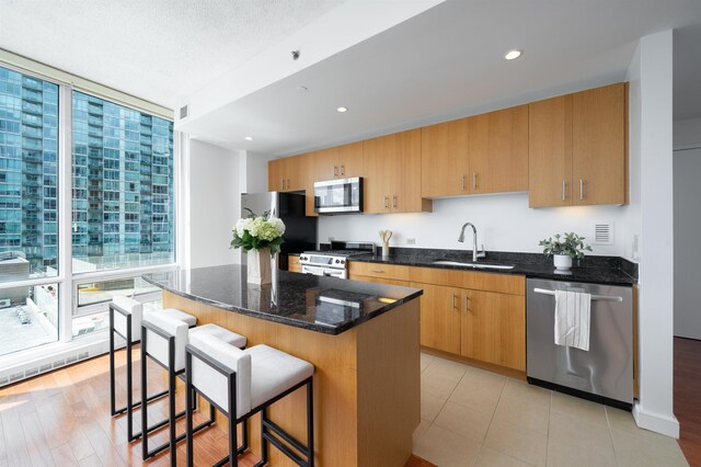 1 Shore Ln Unit 1208, Jersey City, NJ 07310 - kitchen featuring appliances with stainless steel finishes, a wall of windows, a kitchen island, a breakfast bar area, and dark stone counters