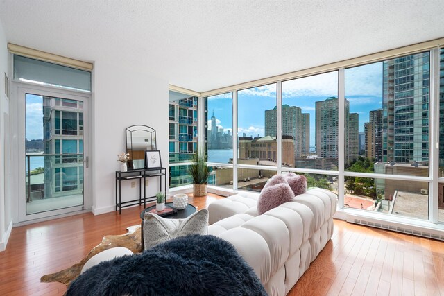 1 Shore Ln Unit 1208, Jersey City, NJ 07310 - living area with wood-type flooring, expansive windows, a skyline view, and a textured ceiling