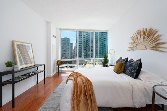 1 Shore Ln Unit 1208, Jersey City, NJ 07310 - bedroom featuring floor to ceiling windows, wood finished floors, and a city view