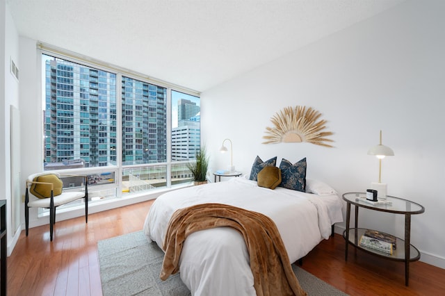 1 Shore Ln Unit 1208, Jersey City, NJ 07310 - bedroom featuring a wall of windows, wood finished floors, and a city view