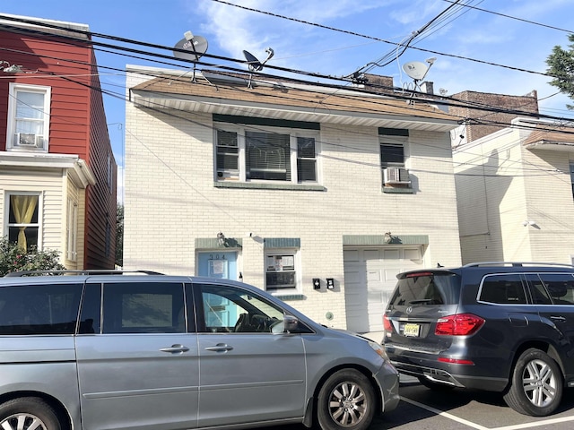 304 51st St, West New York, NJ 07093 - view of front facade with brick siding, cooling unit, and an attached garage