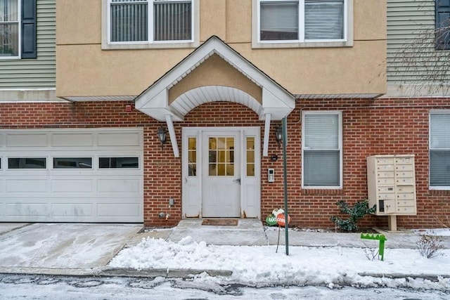 snow covered property entrance featuring a garage