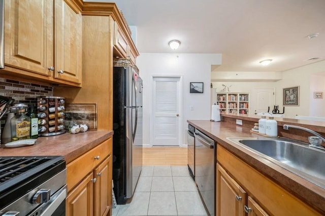 kitchen featuring tasteful backsplash, stainless steel appliances, sink, and light tile patterned floors