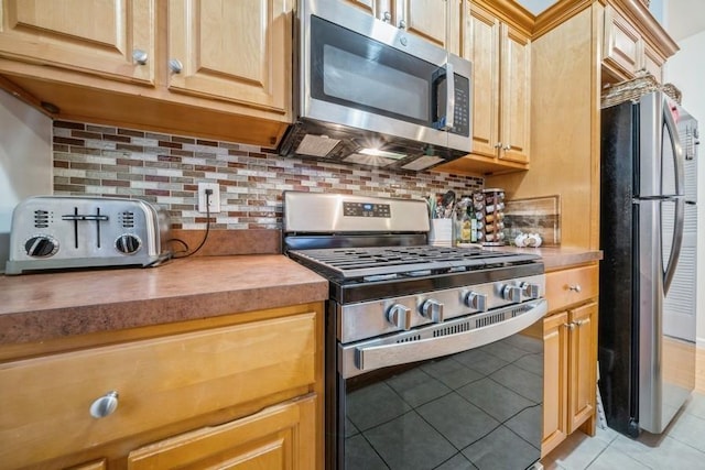 kitchen featuring appliances with stainless steel finishes, light brown cabinetry, light tile patterned floors, and backsplash