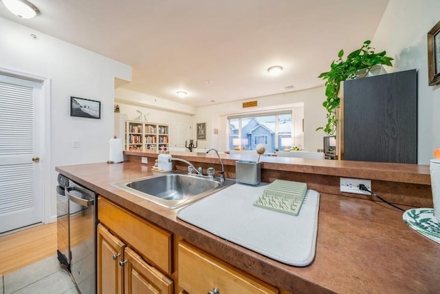 kitchen featuring sink, light tile patterned floors, and stainless steel dishwasher