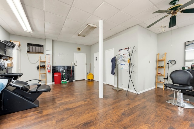 exercise area with a paneled ceiling, dark hardwood / wood-style floors, ceiling fan, and a wall mounted AC