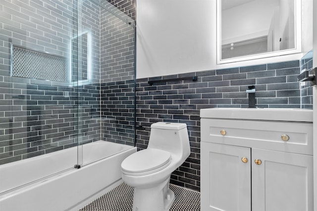 full bathroom featuring tile patterned floors, toilet, bath / shower combo with glass door, tile walls, and vanity