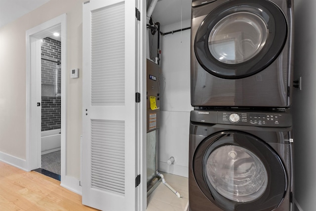 washroom with light hardwood / wood-style floors and stacked washer and clothes dryer