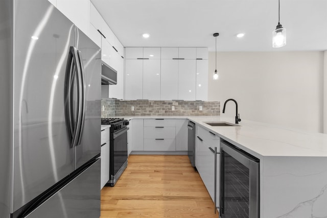 kitchen with appliances with stainless steel finishes, decorative light fixtures, white cabinetry, wine cooler, and kitchen peninsula