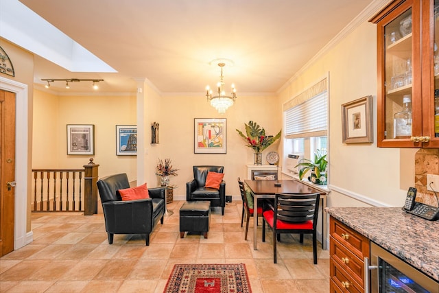 dining area featuring ornamental molding, beverage cooler, rail lighting, and a notable chandelier