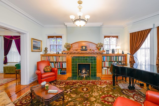 sitting room featuring radiator, crown molding, an inviting chandelier, wood-type flooring, and a fireplace