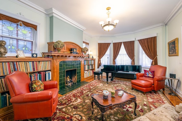 living room with crown molding, wood-type flooring, an inviting chandelier, and a tile fireplace