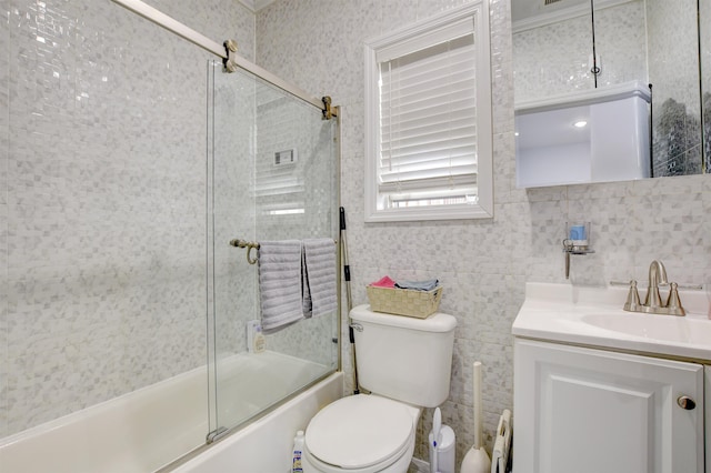 full bath featuring tile walls, bath / shower combo with glass door, toilet, and vanity