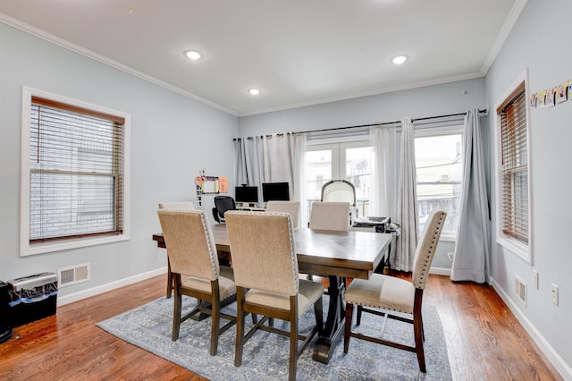 dining space with wood finished floors, crown molding, baseboards, and visible vents