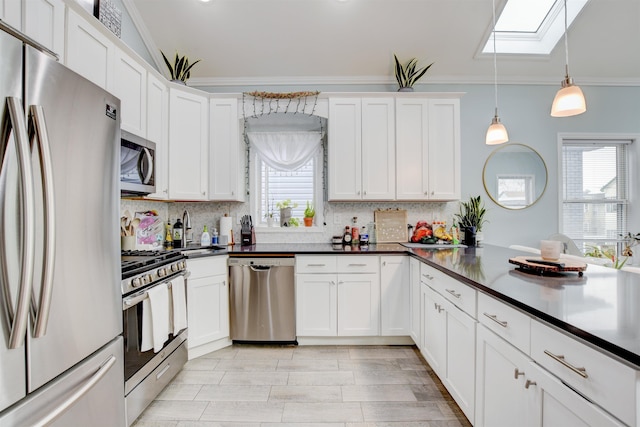 kitchen featuring a skylight, ornamental molding, dark countertops, appliances with stainless steel finishes, and backsplash