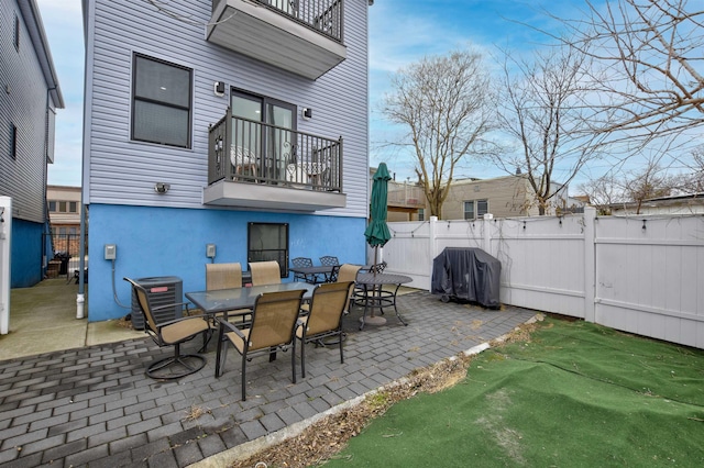 view of patio featuring a balcony, fence, central AC unit, and a grill
