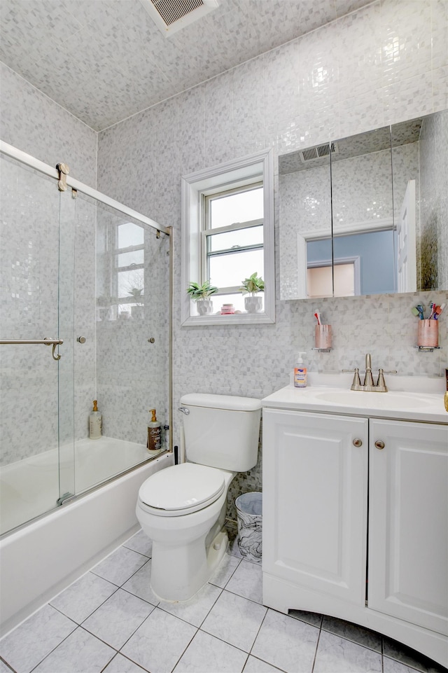 bathroom featuring visible vents, toilet, tile patterned floors, vanity, and shower / bath combination with glass door