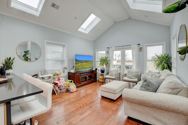 living area featuring high vaulted ceiling, a skylight, light wood finished floors, and visible vents