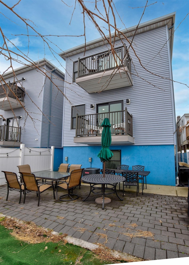 back of property featuring a balcony, fence, and a patio area