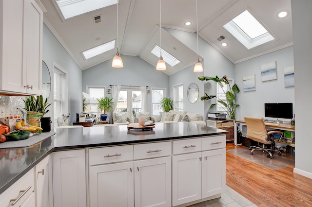 kitchen featuring open floor plan, white cabinets, dark countertops, and a skylight