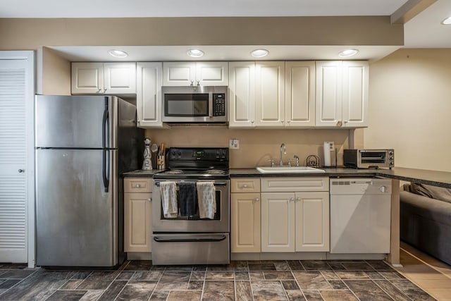 kitchen featuring a sink, dark countertops, white cabinetry, stainless steel appliances, and a toaster