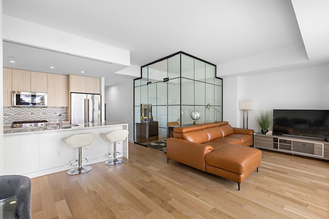 living room featuring sink and light hardwood / wood-style flooring